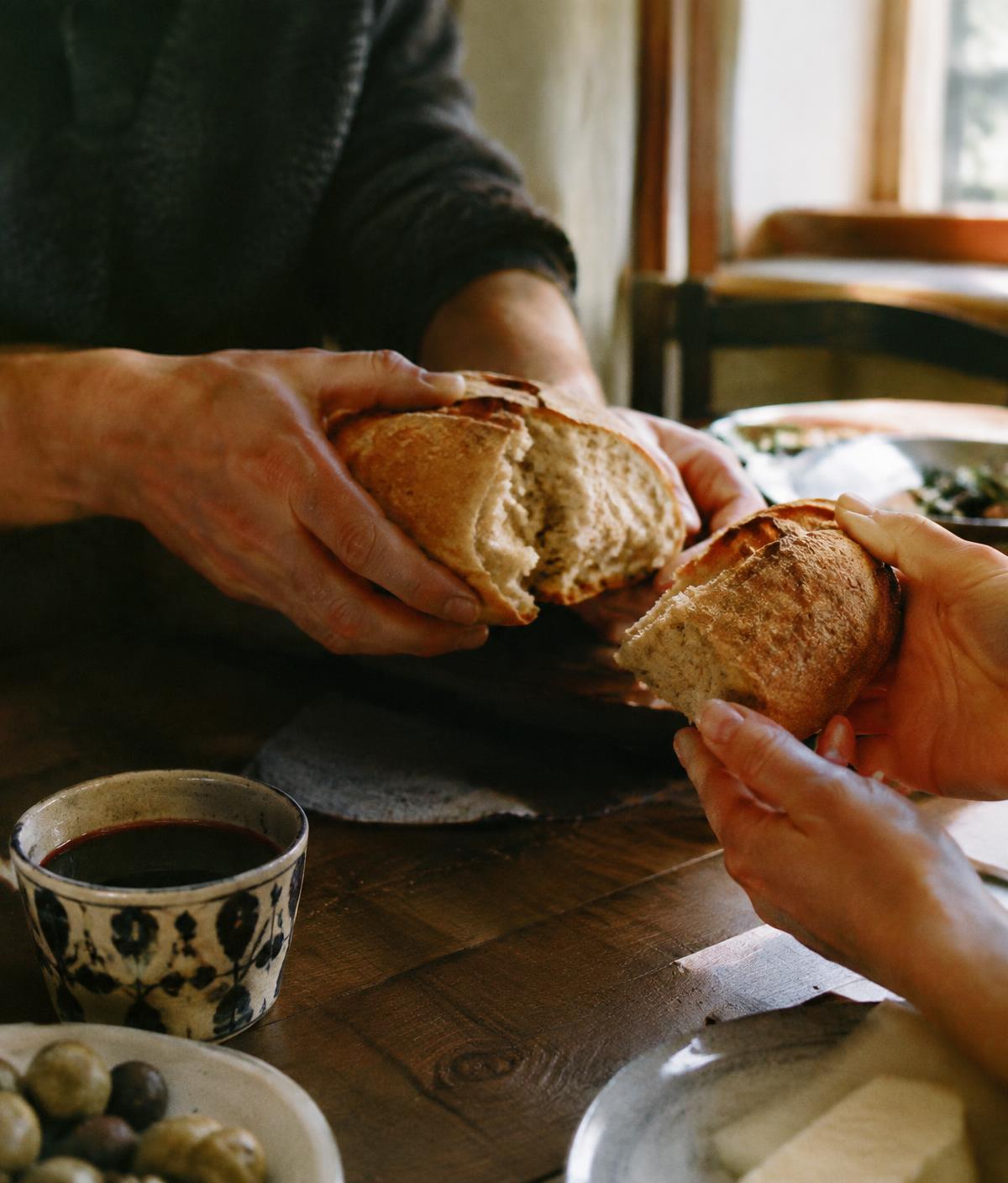 Hands breaking bread across a table